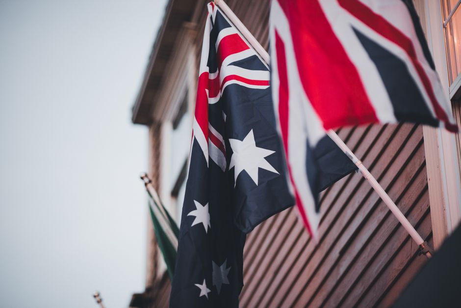 Close-up of Australian and British flags on a building's wooden exterior, signifying national pride.