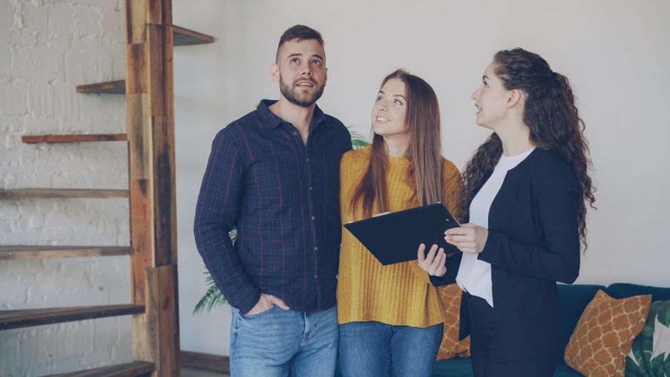 Young couple exploring a new home with their real estate agent, discussing options and features.