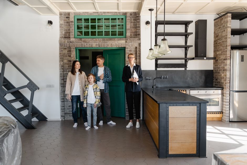 A family with a realtor viewing a modern industrial-style kitchen in a new home.
